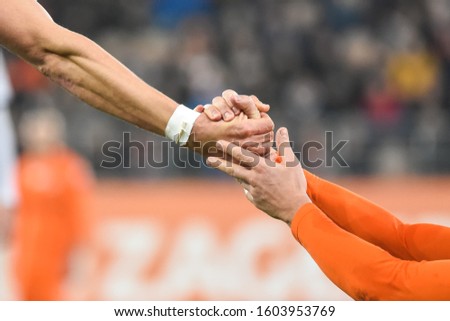 Hands detail - football player helps his oponent. Royalty-Free Stock Photo #1603953769