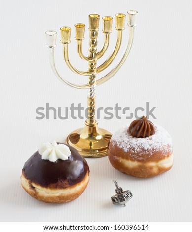Two donuts with chocolate and white cream,  dreidel and Hanuka candles during the Jewish holiday of Hanuka.