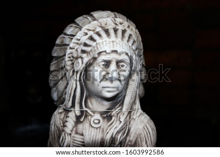 Extremely sad looking stone statue of a native American on a black backround as taken at night