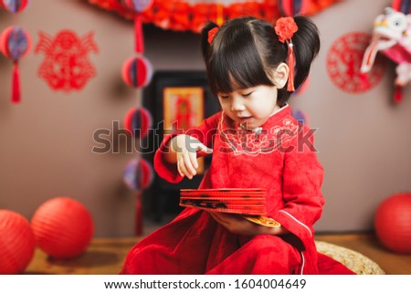 Chinese baby girl with traditional dressing up hand hold Chinese lantern  with " Zhao cai jin bao" meaning "more wealth coming"  celebrate Chinese new year
