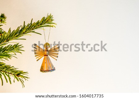 Angel made of straw, hanging in a green branch of a christmas tree, Demnark, January 2, 2020