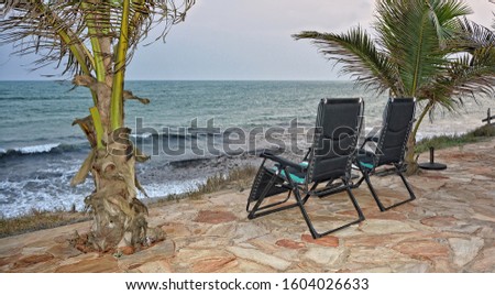 Palm trees, chairs and ocean. Evening. Beautiful seascape. Relax. Secluded ocean coast. Travel and Vacation.