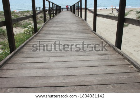 Photo of a wooden bridge on the beach. Sea in the background.