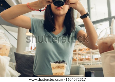 Asian woman is taking a photo of her blueberry cheesecake.