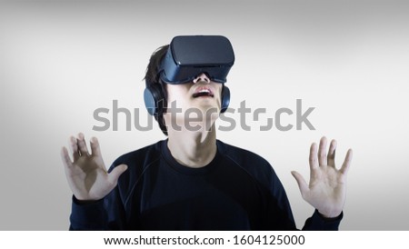 Man wearing virtual reality goggles. Studio shot, gray background