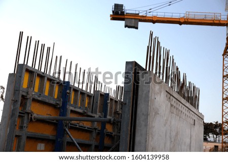 Abstract angle of a concrete and rebar structure being built on a construction site, showing the tail end of a tower cranes balance weights. Shot in colour.
