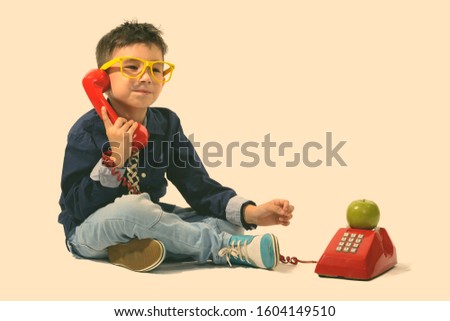 Studio shot of cute boy talking on old telephone