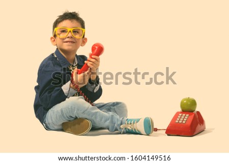 Studio shot of cute happy boy smiling and holding old telephone while looking up