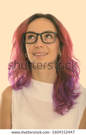 Face of young happy woman smiling while thinking and looking up