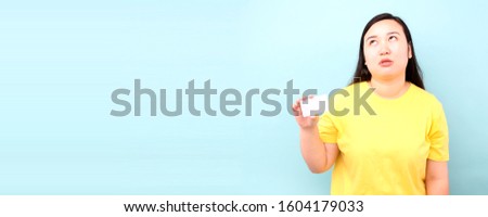 Portrait of a asia woman sad ,holding  credit card isolated over blue background ,in studio With copy space.