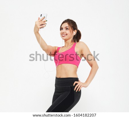 portrait of a smiling fitness woman with smartphone. Selfie time. over white background