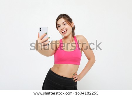 portrait of a smiling fitness woman with smartphone. Selfie time. over white background