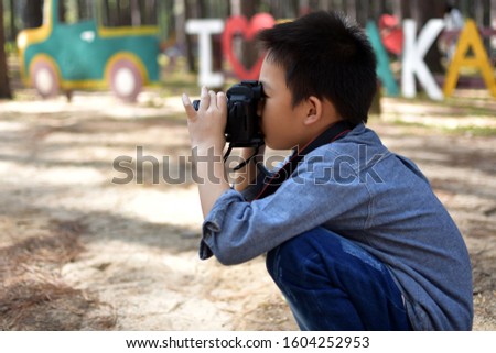 Asian boy takes picture with a camera 