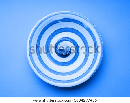 Classic blue color of 2020 pastel ceramic dish with hypnotizing spiral. Abstract food, tableware crockery concept
