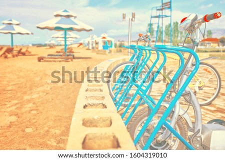 Parking spaces for bicycles with bikes on the ocean front on the background of beach umbrellas