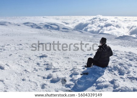 Lonely mountaineer get rest on snowy mountain high above the clouds. Happy climber enjoy in view from top of Dry Mountain, Serbia