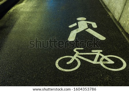 White bicycle and the man symbols on the wet or damp pavement asphalt