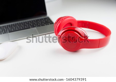 Photo of stylish modern computer or notebook and red headphones over white background. Trendy office, freelance workplace.