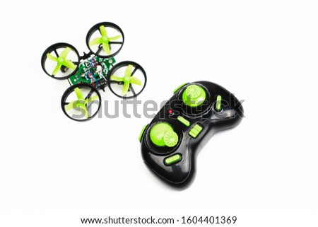 small quadcopter and remote control on white background