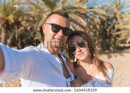 Young happy couple taking selfie on a palm beach . Summer vacations concept. 