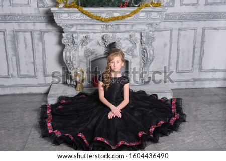 girl in elegant black dress is sitting in the gray room interior