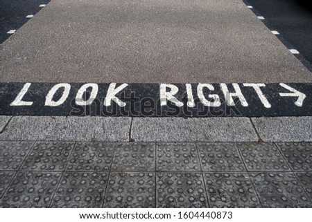 "Look right" road marking on a pedestrian crossing, reminding pedestrians about left hand driving in the UK. Selective focus