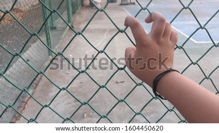 Hand of fat boy push the net in the park. His fingers touch the net. Texture abstract background. Space for text