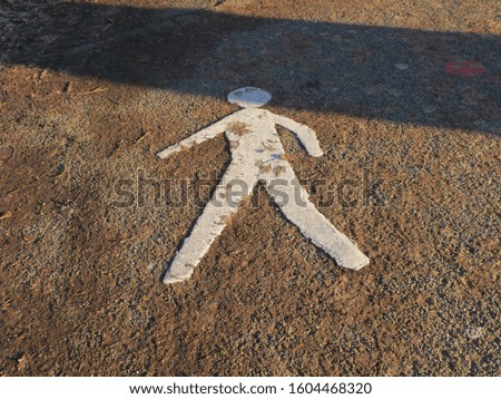 a sign of a pedestrian on an asphalt sidewalk
