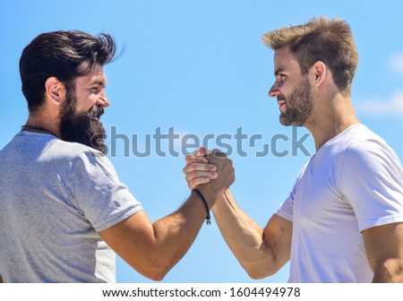 Handshake arm wrestling style. Strong and muscular arms. Successful deal handshake blue sky background. Men shaking hands at meeting. Friendly handshake gesture concept. Friends or competitor.