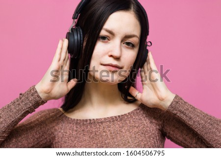 Image of a happy young beautiful woman posing isolated over pink wall background listening music with earphones