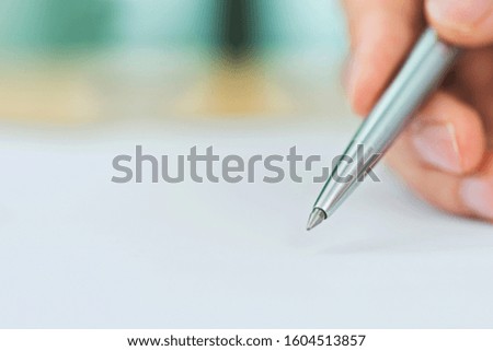 Hand with pen signing on paper.