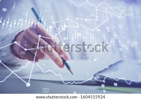 Financial forex graph displayed on hands taking notes background. Concept of research. Double exposure