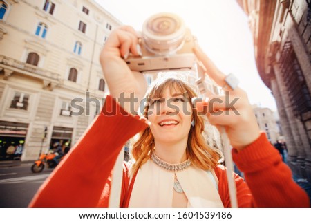 Happy traveler photographer woman holding camera on european street and taking picture.