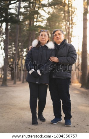 a happy elder couple is smiling and take a picture together in the forest in the winter season.