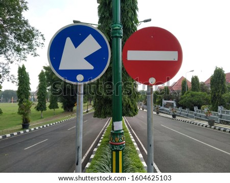 Traffic signs must enter the left lane and entry prohibited on the right lane, and perspective of the road, trees, poles and buildings also the sky as background.