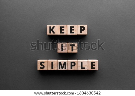 Keep it simple - word from wooden blocks with letters, to make something easy, keep it simple concept, gray background Royalty-Free Stock Photo #1604630542