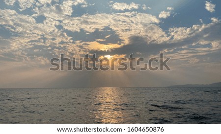 The rays of the sun make their way through the clouds on the river landscape at sunset.