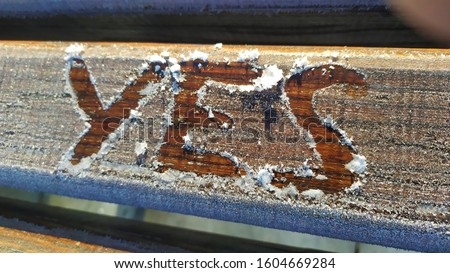 Sign "YES" on wooden frosted plank. Hoary wooden surface and drawn by finger inscription YES.