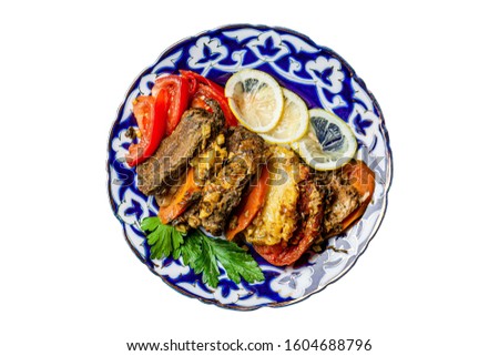 Traditional oriental cuisine. Dish for the holiday of Navruz from meat, fish, pineapple, paprika, tomato and lemon. Serving dishes in Uzbek plates. Copy space, isolated image