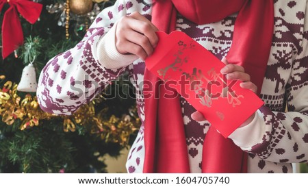 Celebration of the Chinese Lunar New Year. Traditional flower patterns on Red Packets Hong Bao with golden words mean Happy New Year. Woman opens the envelope and takes out the money. Christmas decor.