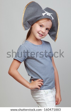 Lovely joyful girl in a pirate hat on a gray background