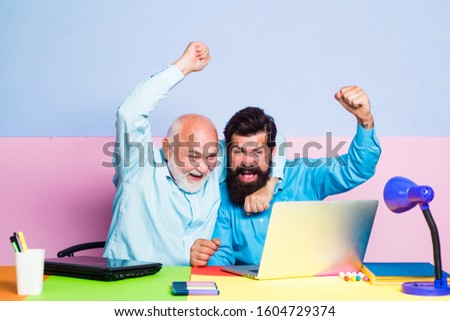 Funny photo of businessman wearing shirt working with laptop at table. Two colleagues working together at office on color background