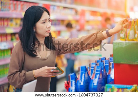 woman making shopping decision for sweet in supermarket, stands in store