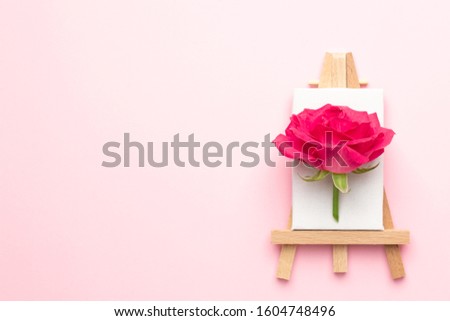Canvas for painting with rose flower on pink background copyspace, spring and creativity concept