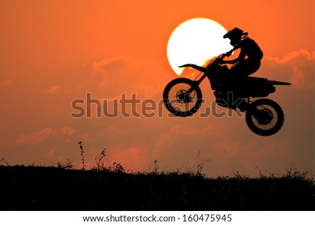 silhouette of a motorcyclist on a background of dark sky in sunset 