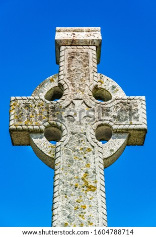 Howth, Ireland: Old stone celtic cross on a bright clear blue sky background