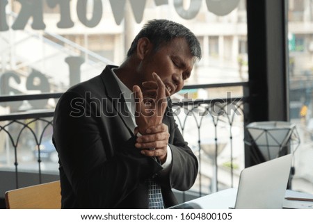 Senior asian businessman experiencing wrist pain, office syndrome concept.                               