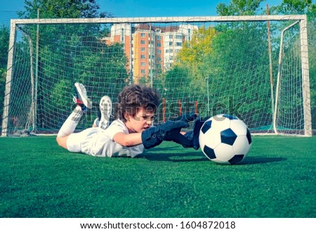 Young soccer goalie attempting to make a save. little soccer goalkeeper with gloves. Kids - soccer champion. Boy goalkeeper in football sportswear on stadium with ball. Sport concept. Selective focus.