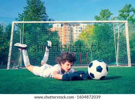 Young soccer goalie attempting to make a save. little soccer goalkeeper with gloves. Kids - soccer champion. Boy goalkeeper in football sportswear on stadium with ball. Sport concept. Selective focus.