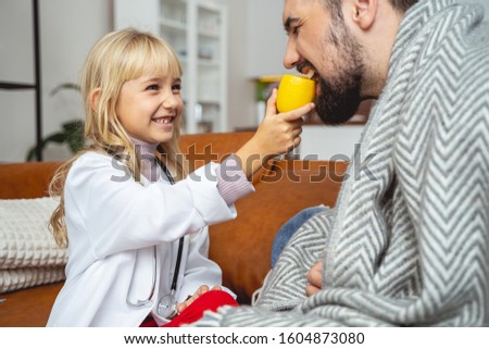 Young man biting citrus while cute daughter looking at him and smiling stock photo